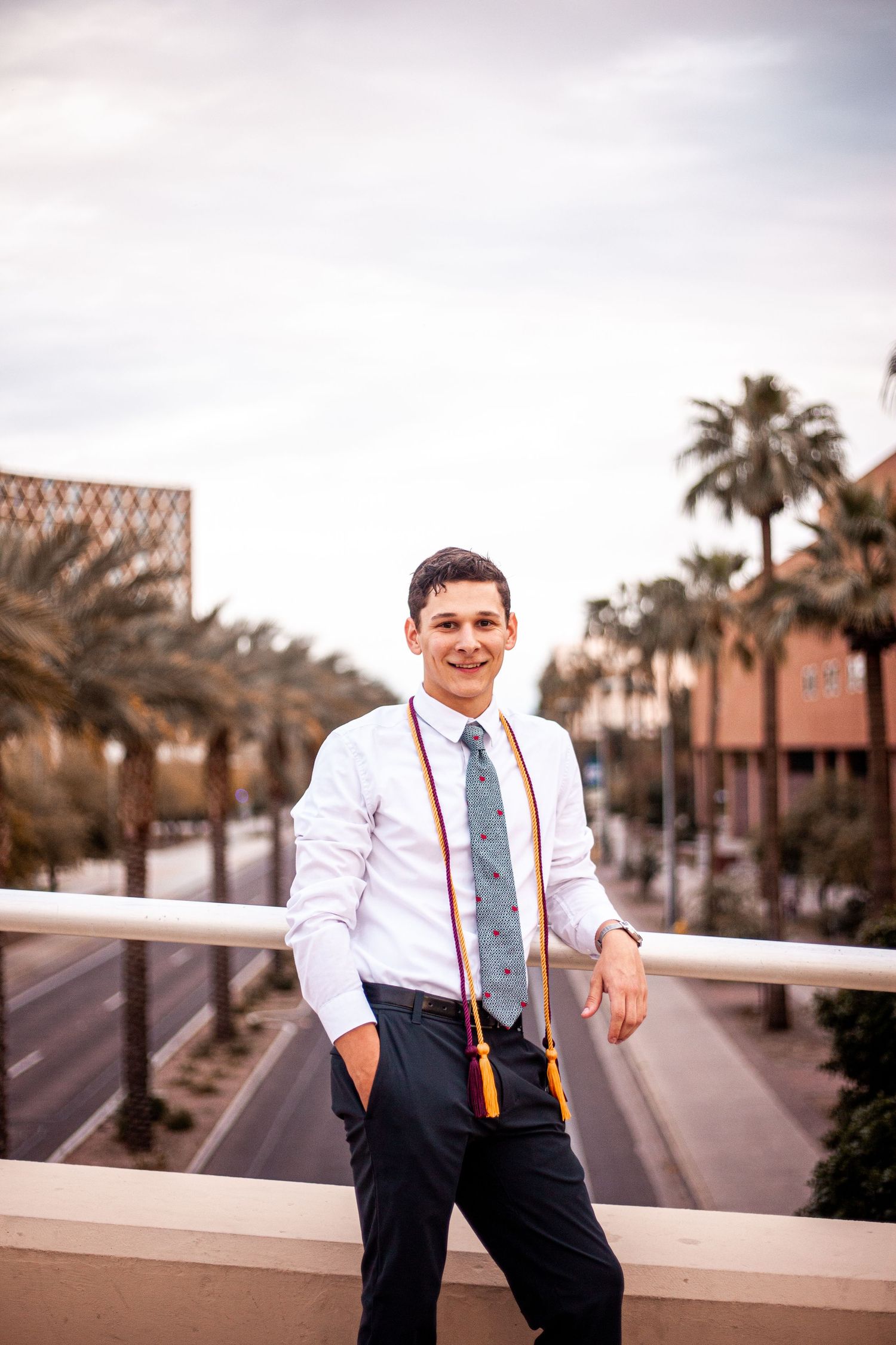 Professional portrait on a palm-lined path wearing business attire with suspenders.