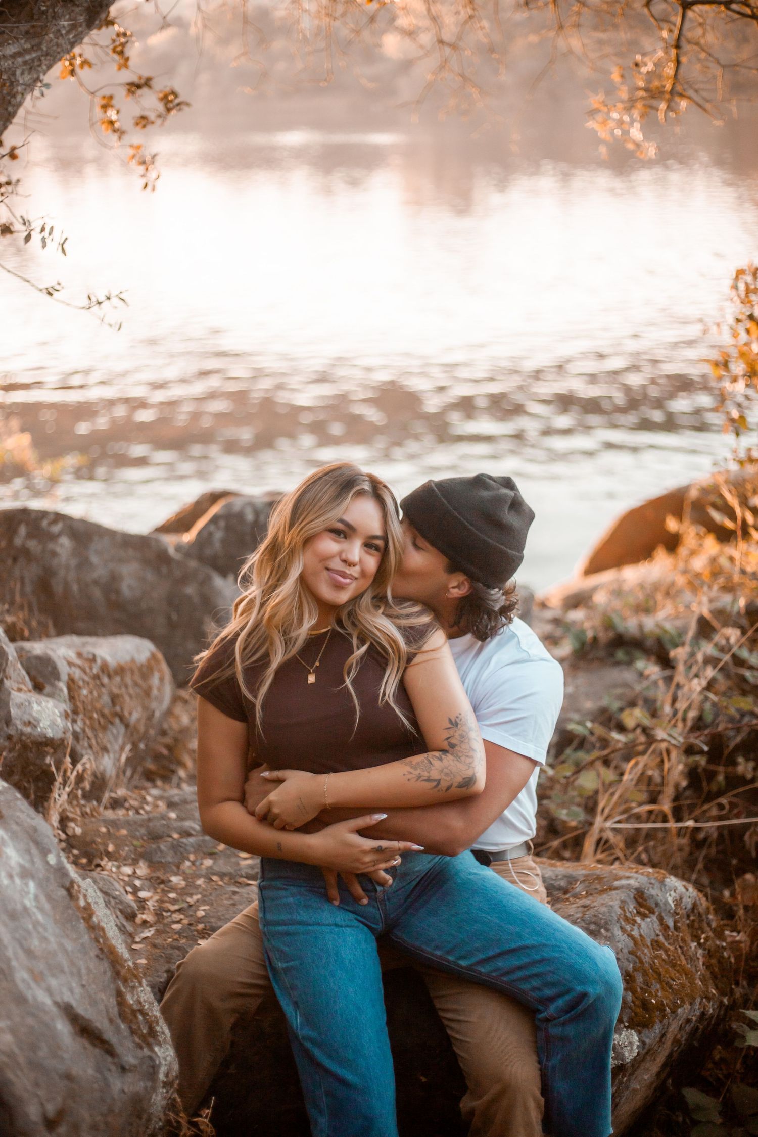 Couple sharing intimate moment on rocky shore at sunset.