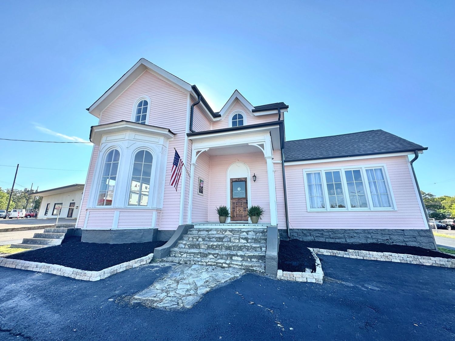 Exterior views of a pink church building with white trim and stone foundation under blue sky.