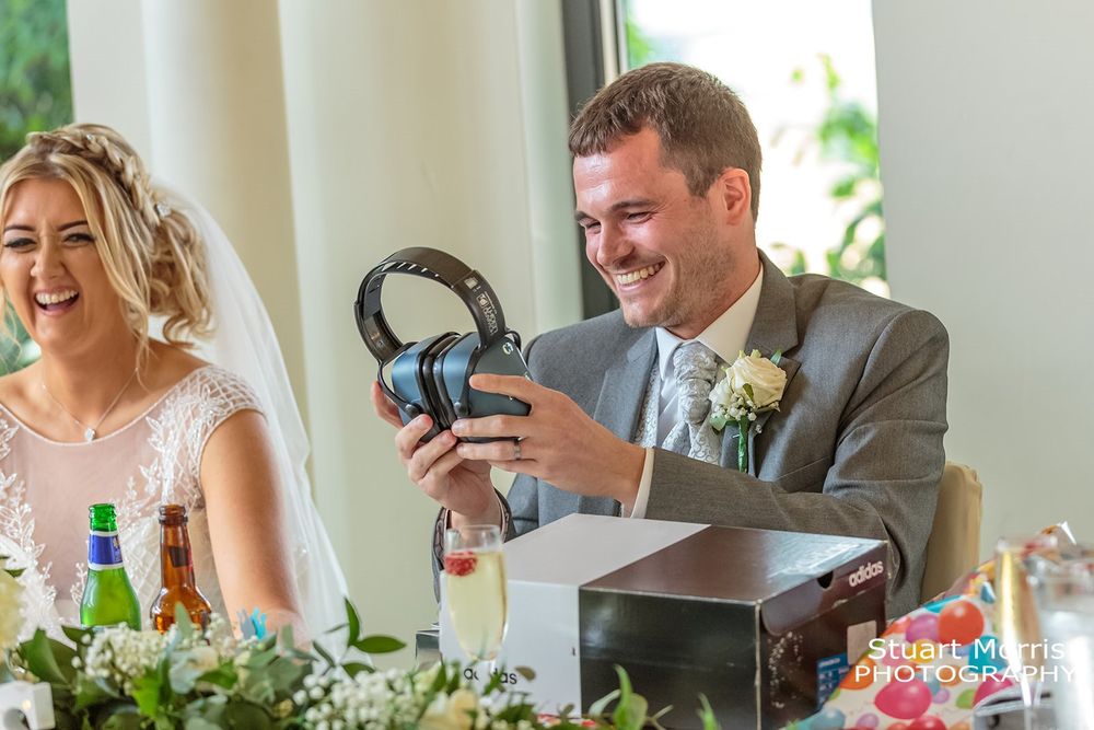Groom smiling at his ear defenders gift from the brides father. West tower wedding speeches.
