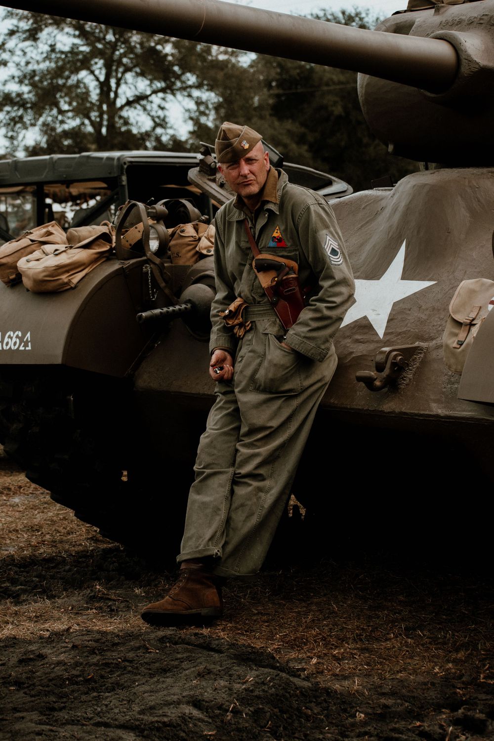 Military personnel inspect and maintain vintage tanks during historical demonstration.
