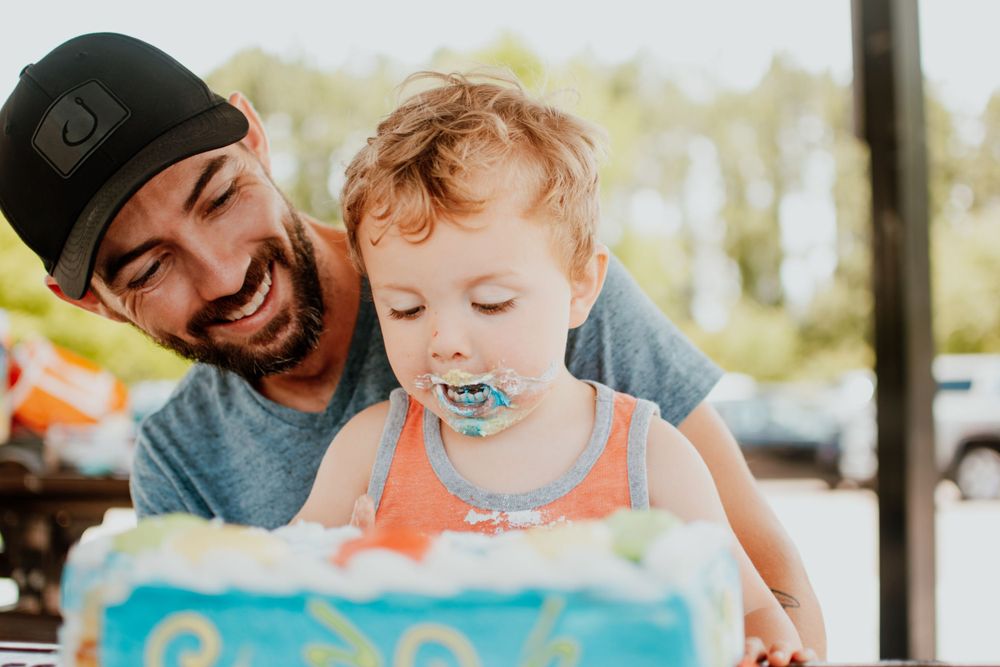 Candid moment of joy shared over a blue birthday cake at an outdoor celebration.