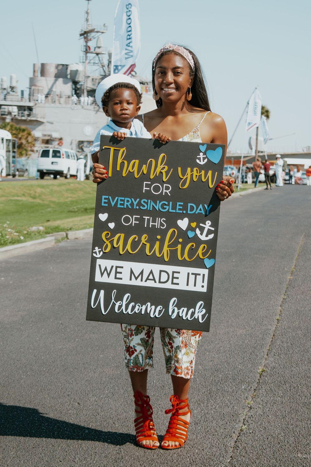 Children hold decorative welcome signs with heartfelt messages at a military homecoming event.