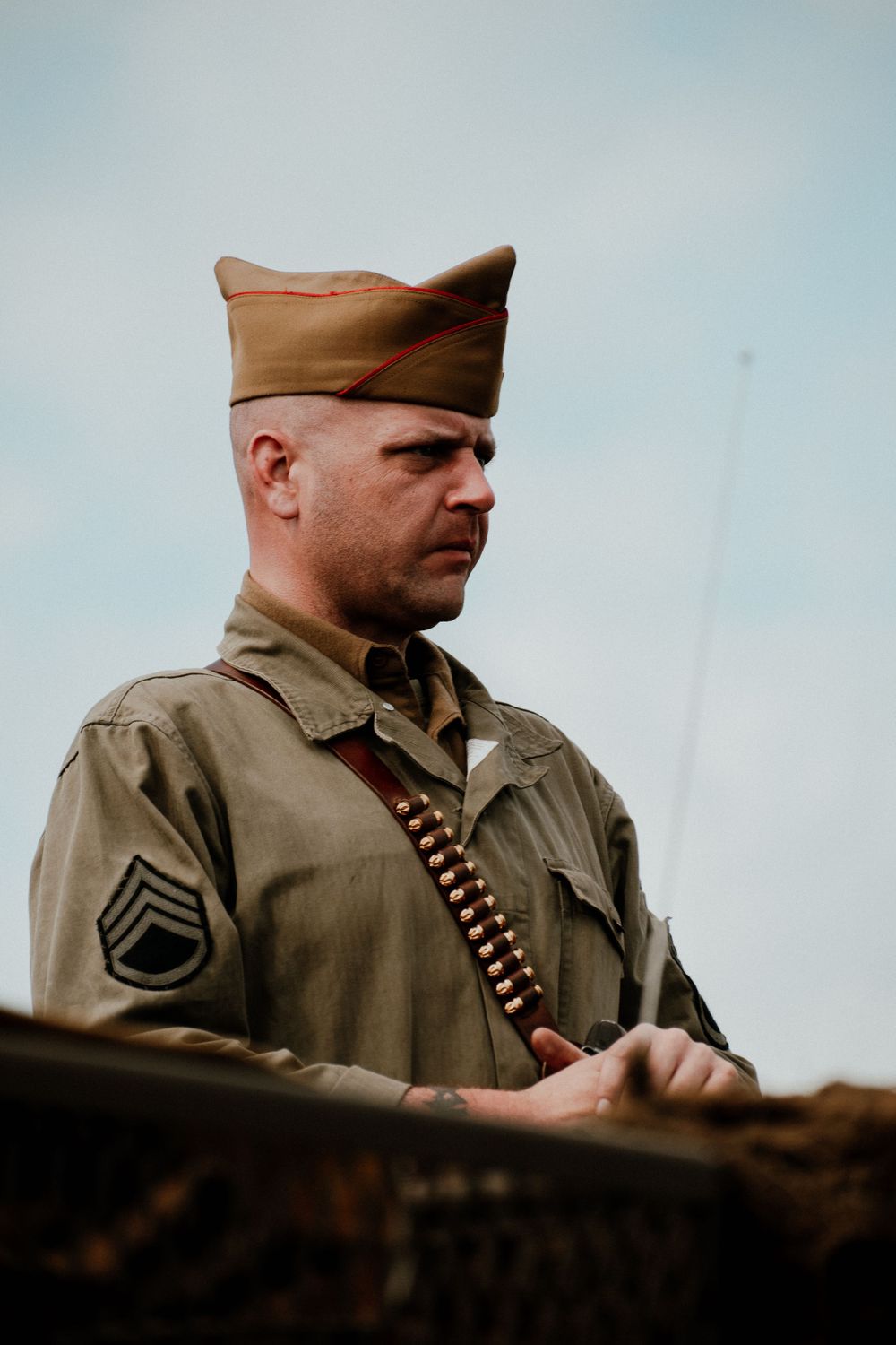 Military service member in uniform photographed in profile against cloudy sky.