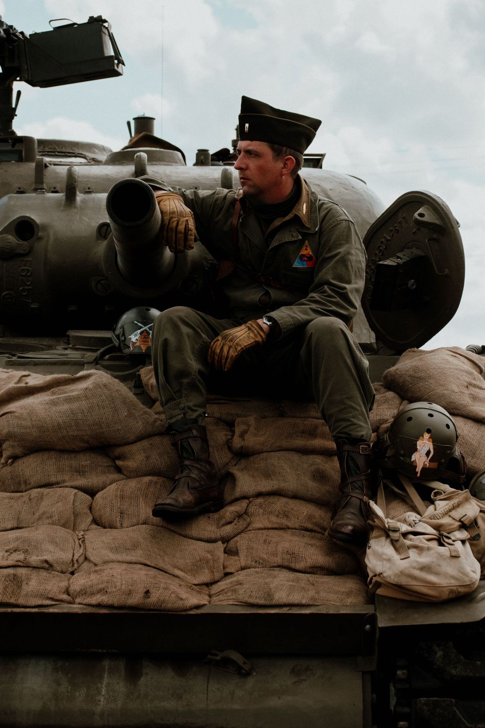 Soldiers in vintage military uniforms rest on sandbags during historical reenactment.