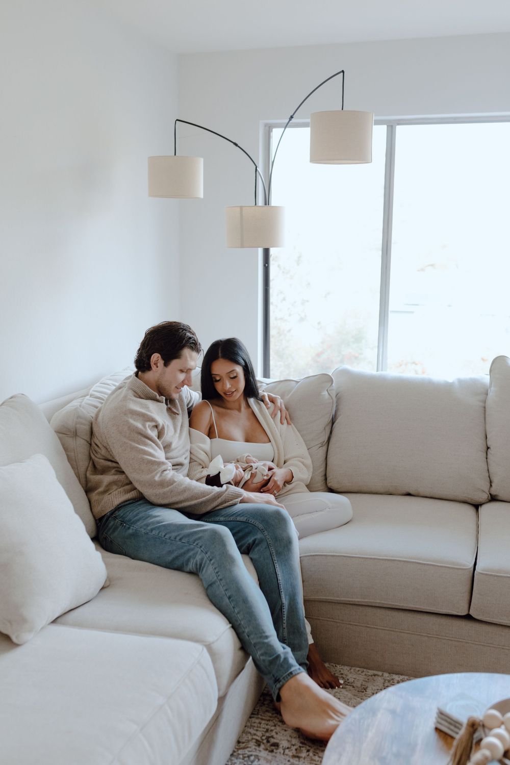 Cozy couple relaxing on white sectional sofa under modern arc floor lamp.