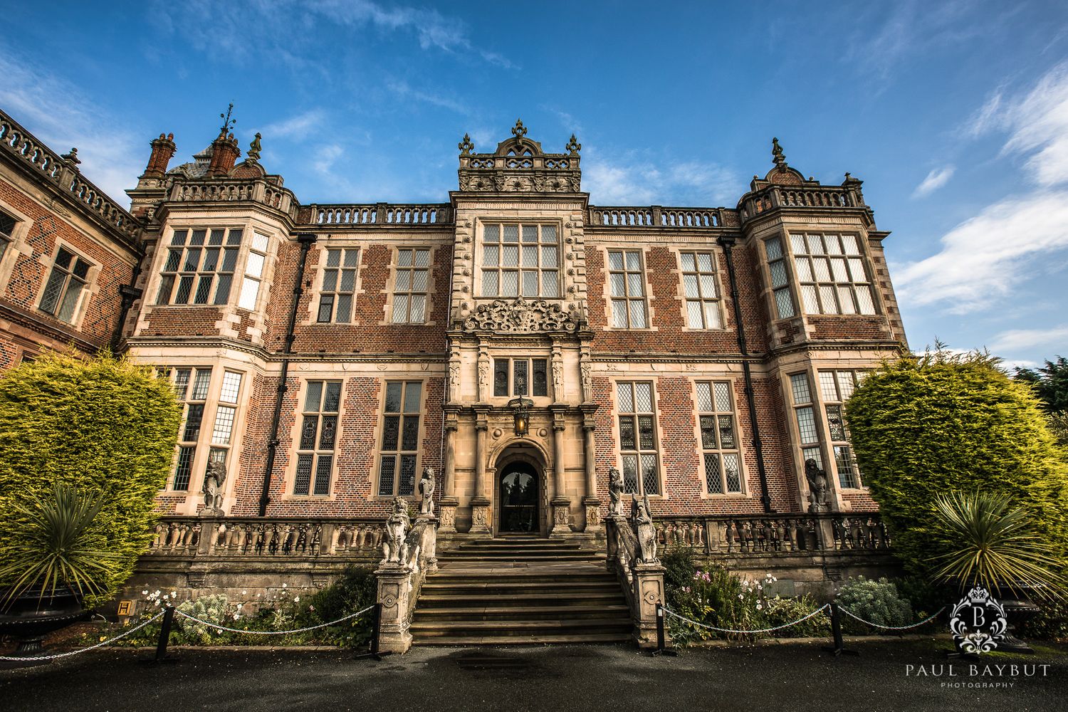 Stunning Victorian Gothic manor house facade under blue sky with grand entrance stairs.