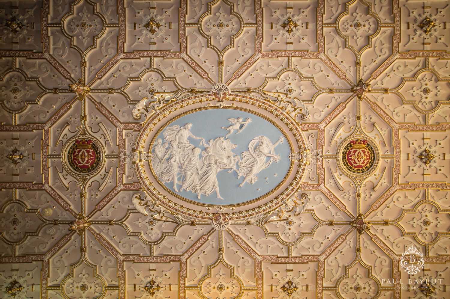 Decorative ceiling with classical relief artwork in oval medallion surrounded by geometric patterns.