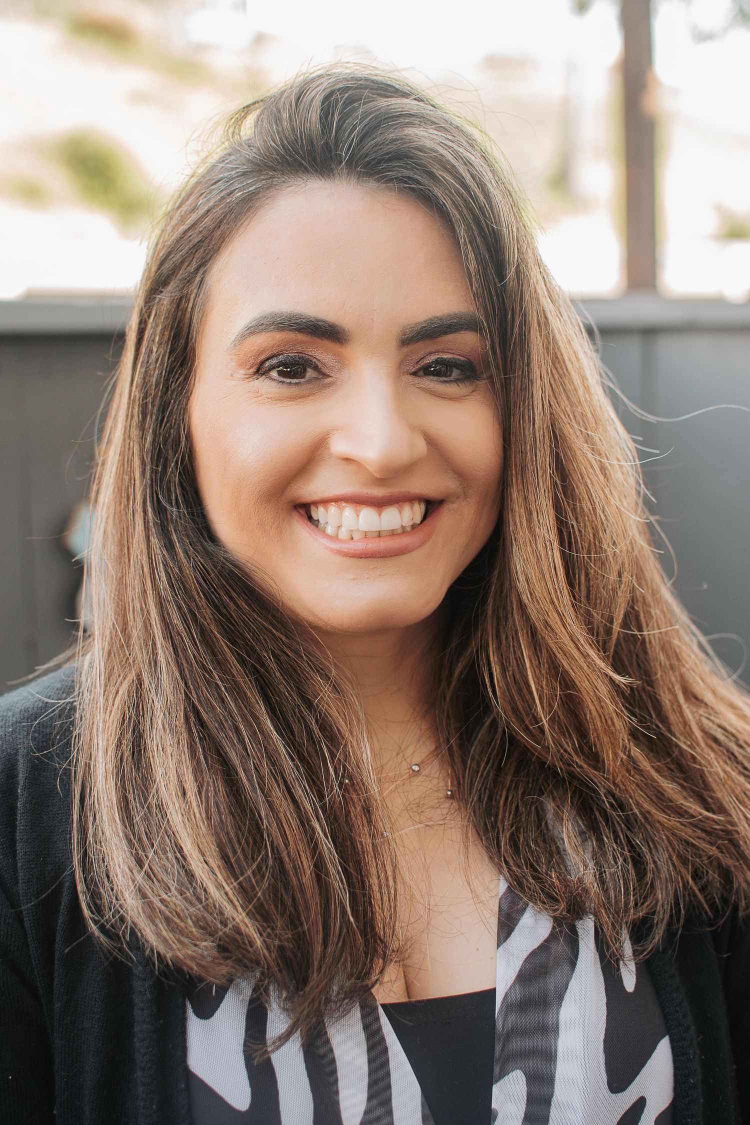 A natural lifestyle portrait with long brown hair and black cardigan against neutral background.