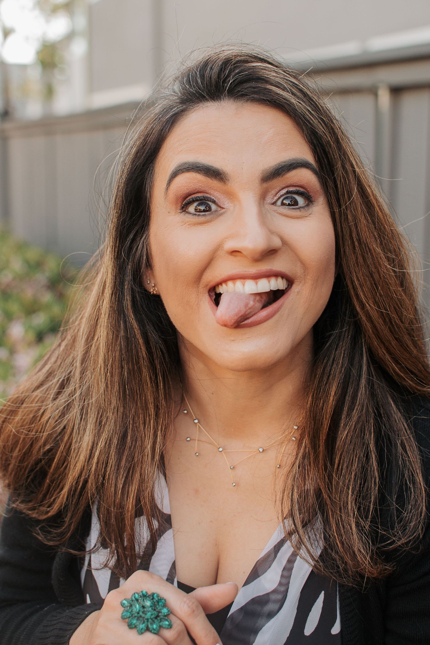 A playful portrait showing personality with a black cardigan and statement jewelry.