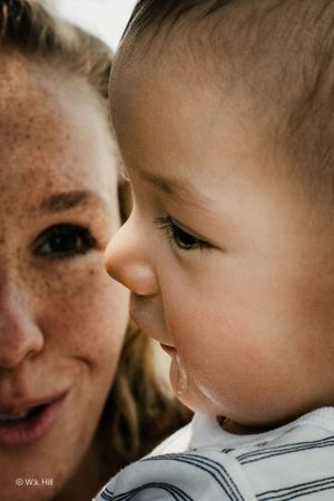 A tender close-up portrait showing freckles and eyelashes in warm intimate lighting.