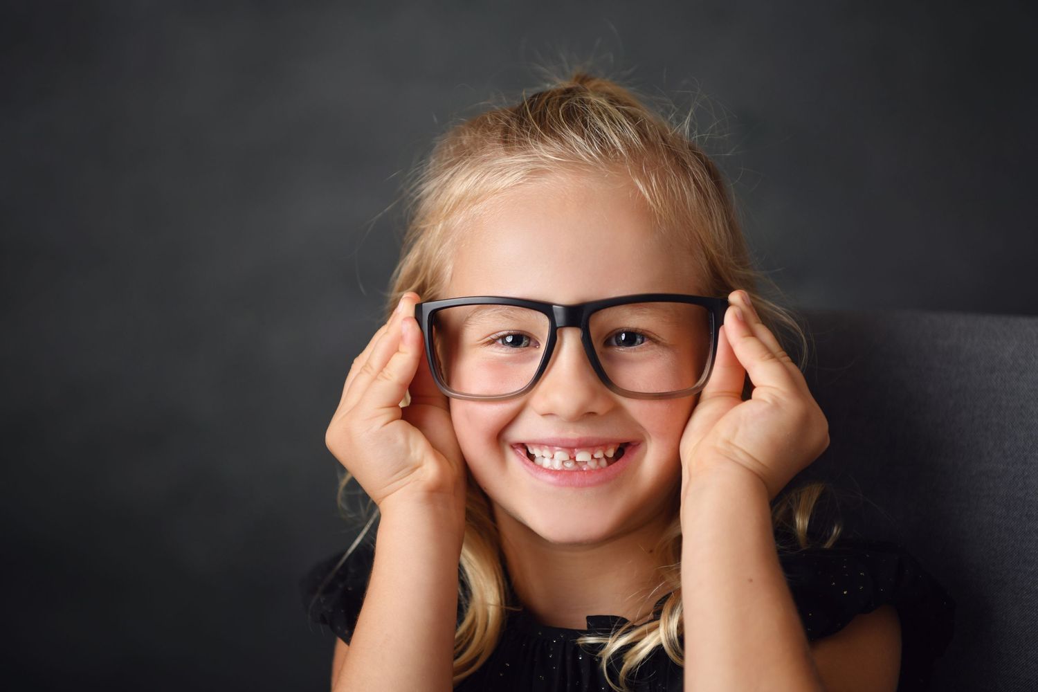 Studio portrait with glasses against dark background.