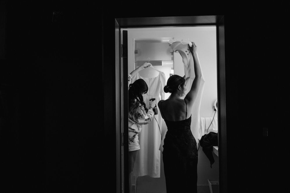 Silhouettes of people getting ready in a doorway captured in dramatic black and white lighting.