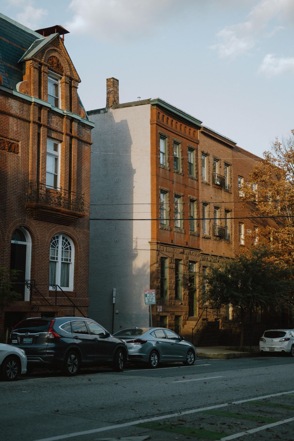 Historic brick buildings with ornate architecture and parked cars along an urban street.