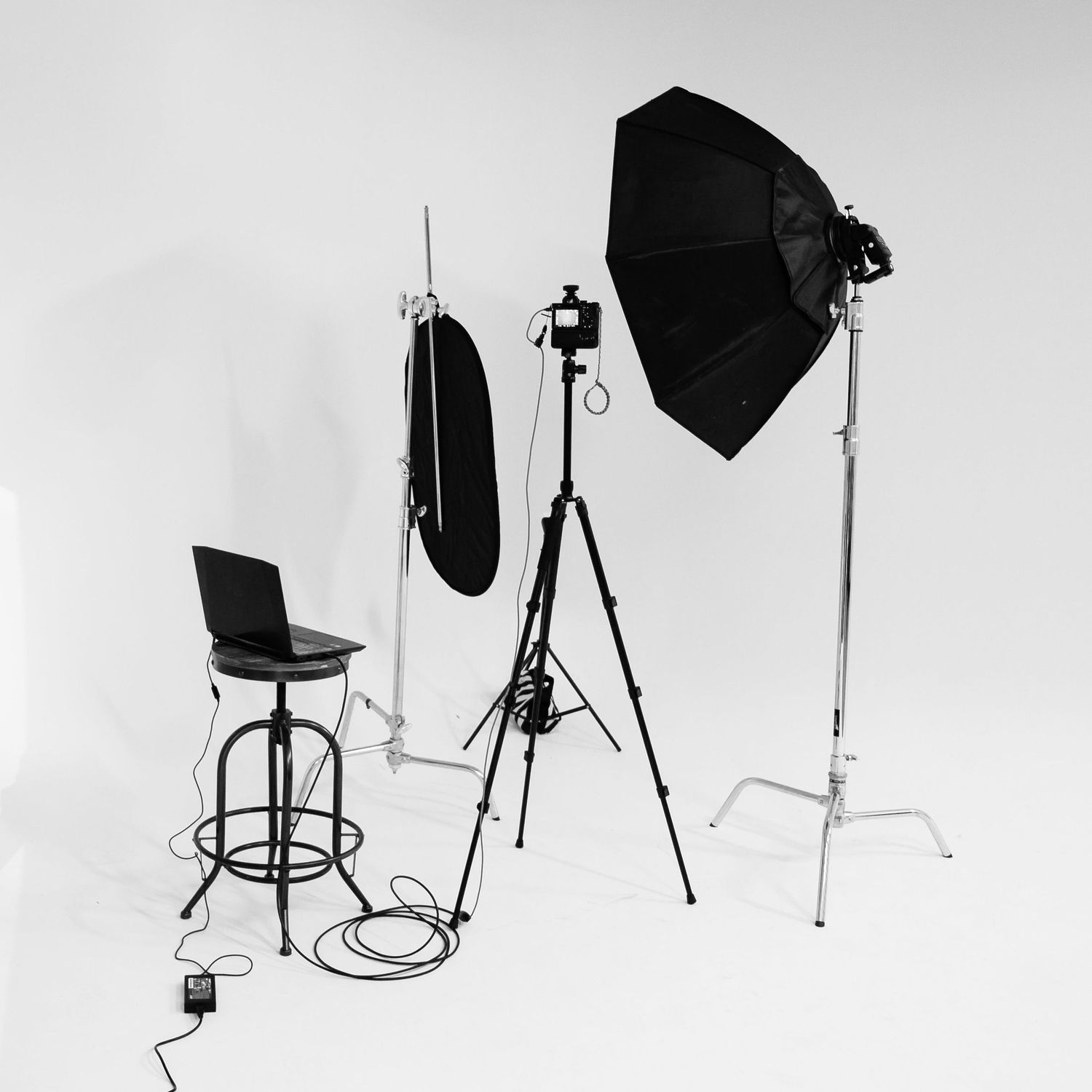 Photography studio setup with lighting equipment, softbox, and high chair against white background.