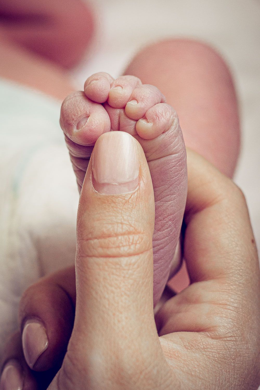 close up of baby's foot and mums thumb to show baby details of newborn baby