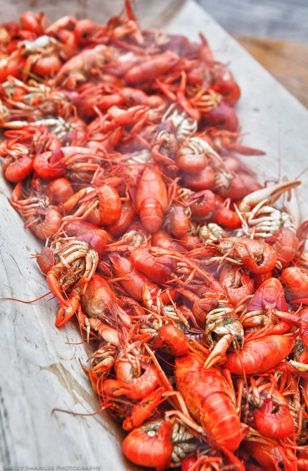 Fresh red crawfish piled on white paper ready for a seafood boil.