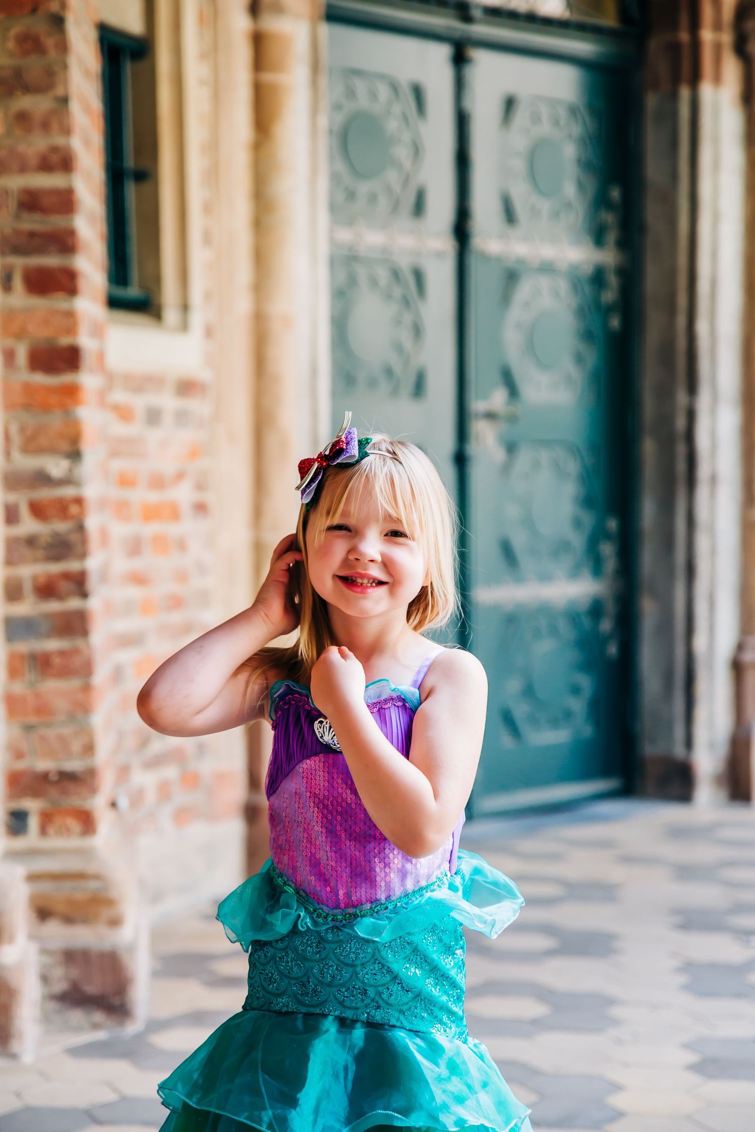 A joyful dance pose in a sparkly purple and turquoise costume by a vintage door.