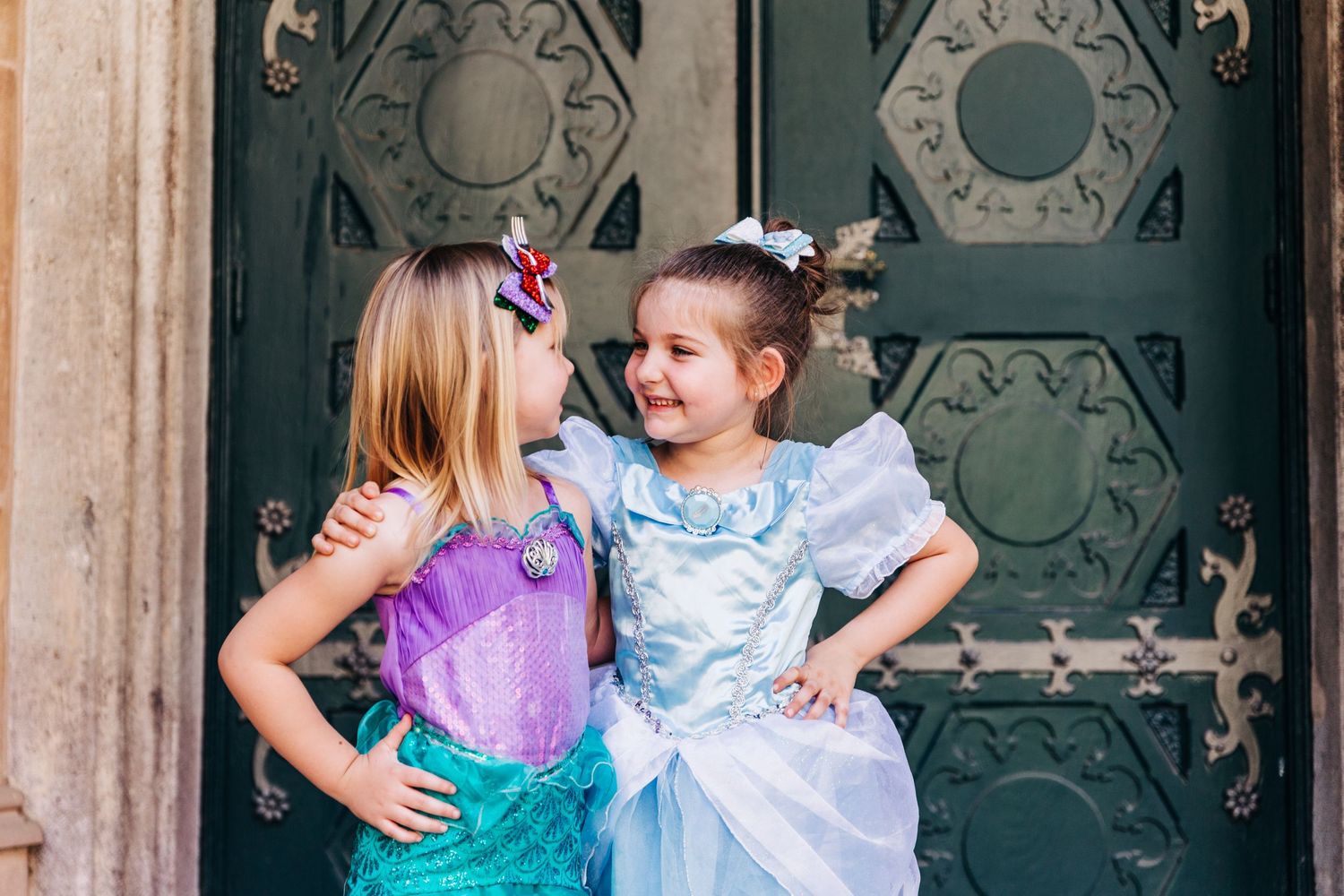 Two friends in costume share a playful moment in front of a dark vintage door.