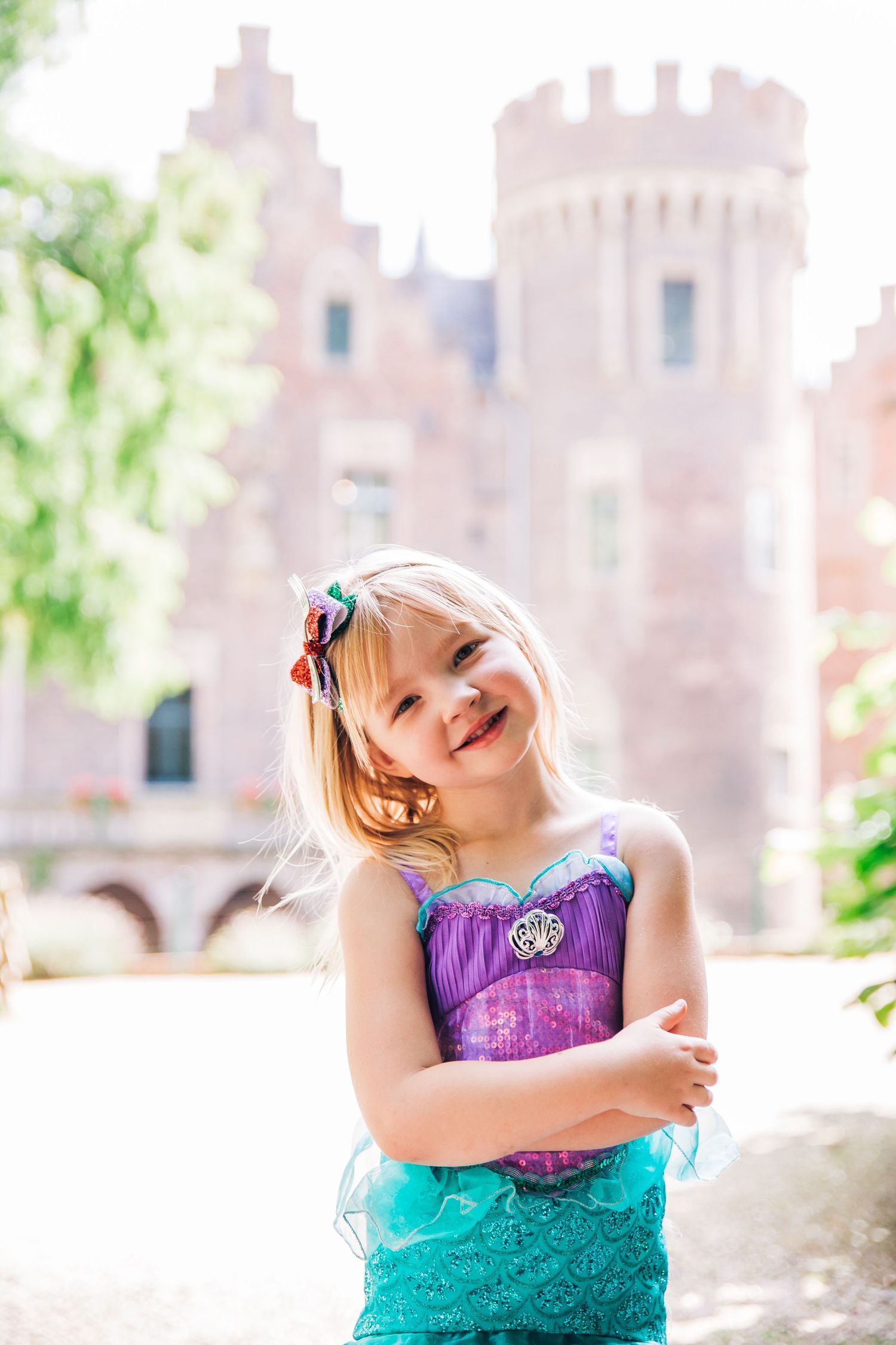 Joyful pose in princess costume with fairytale castle in soft focus background.