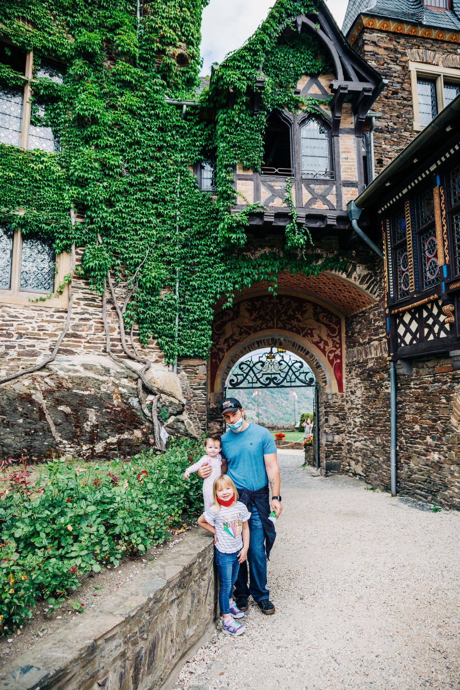 Visitors explore an ivy-covered stone archway entrance at a medieval castle.