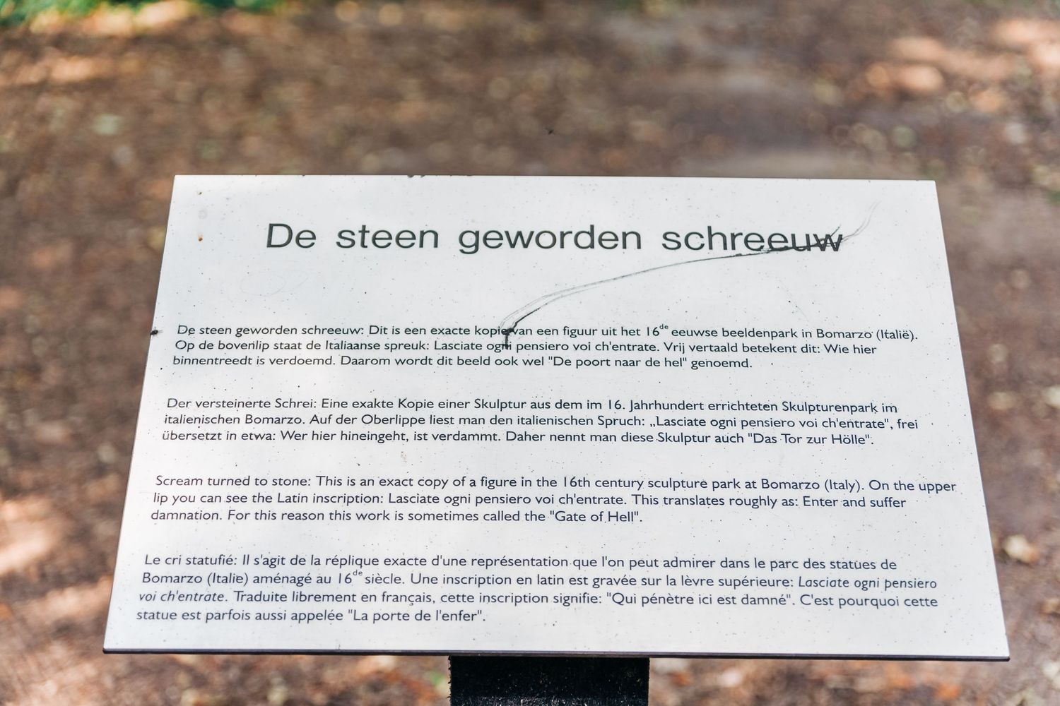 Informational plaque with multilingual text displayed in an outdoor setting.