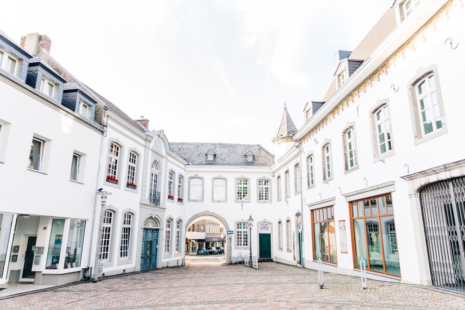 White architectural courtyard with arched passageway and historic European building facades.