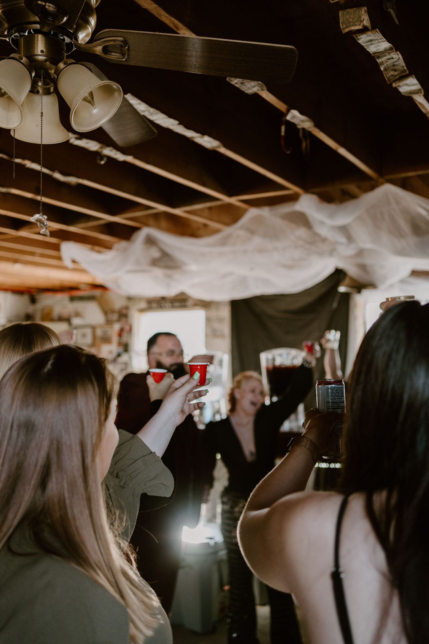 Guests celebrating at a dimly lit party with decorative cobwebs and Halloween decor hanging from the ceiling.