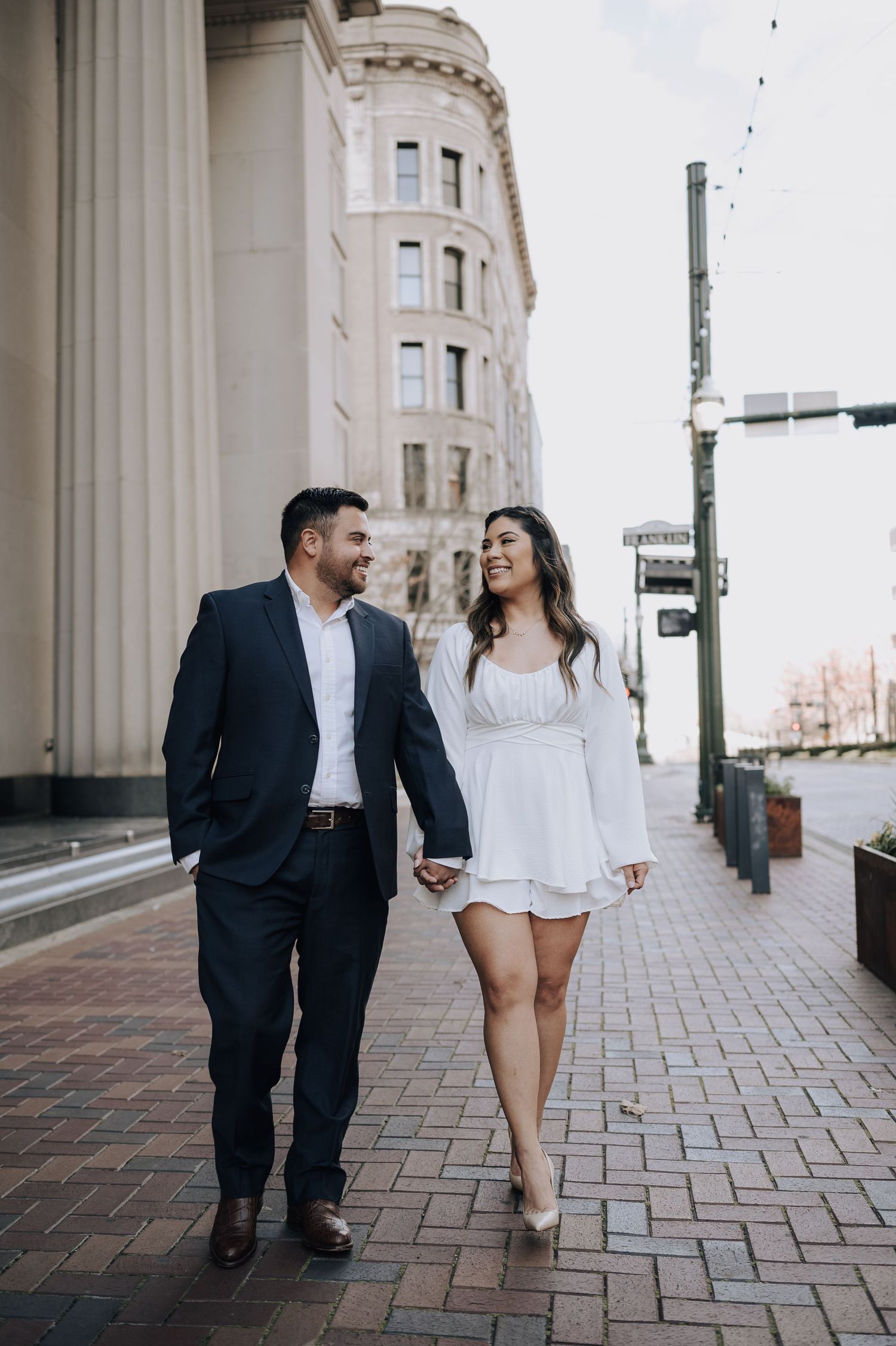 Houston area couple's engagement session. They are holding hands and walking across Franklin Street in downtown.
