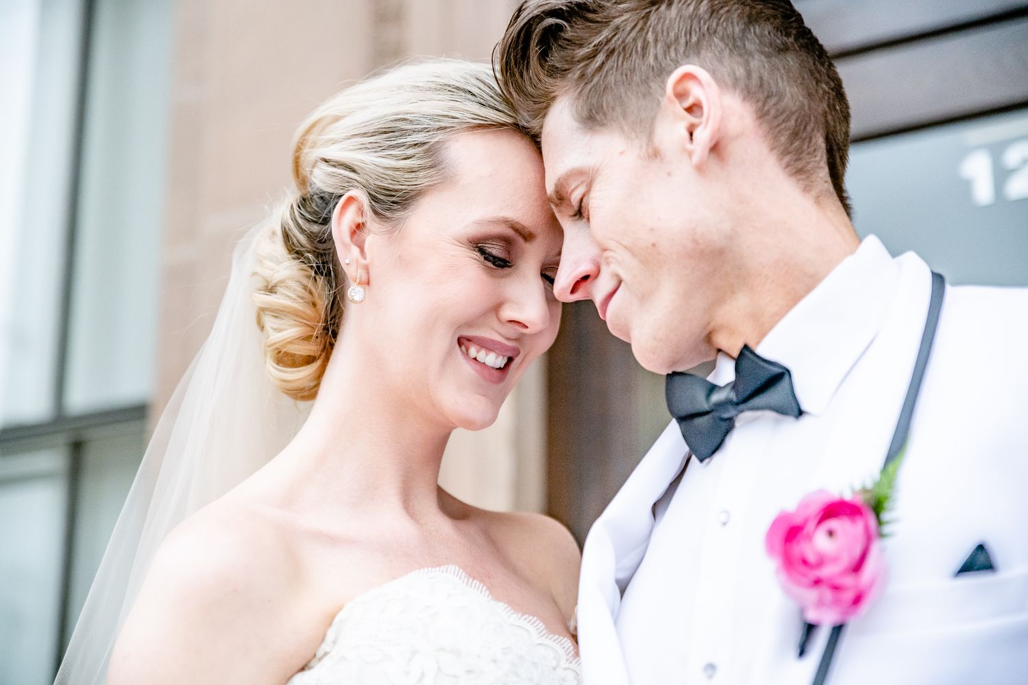 A romantic bride and groom share an intimate moment outside with a pink rose boutonniere detail by Stephanie Coulter Photography