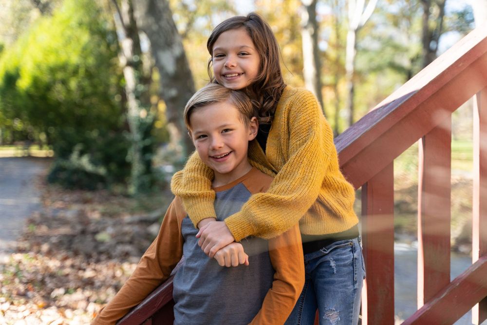 Warm embrace shared on wooden stairs surrounded by autumn foliage.