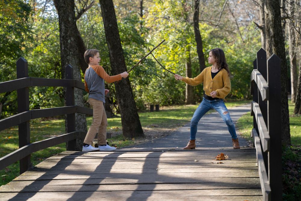 Two people striking playful poses while having fun on a wooden bridge in a park.