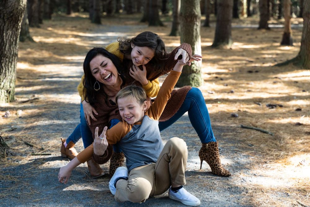 Playful family moment captured on a sunny forest path.