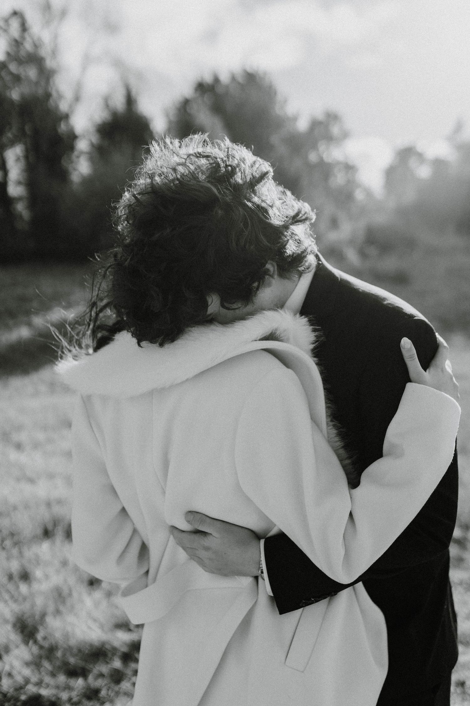 Artistic black and white photo captures romantic wedding moment in natural setting.