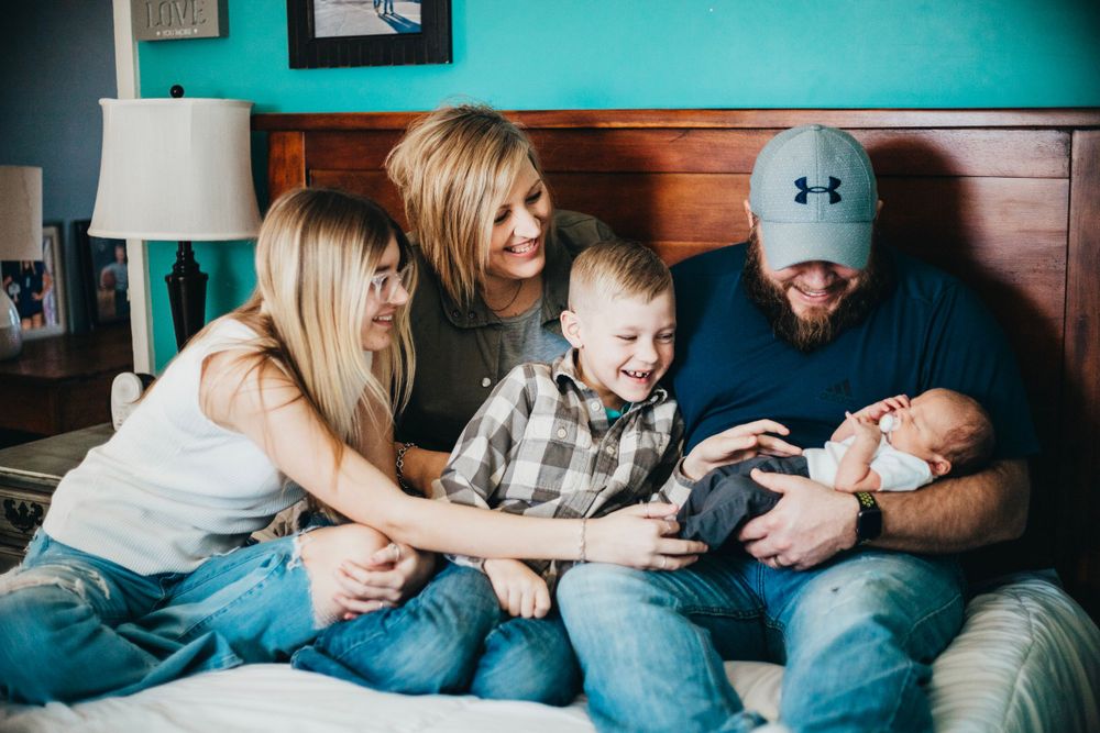 Family sharing tender moment together while relaxing on bed with infant.