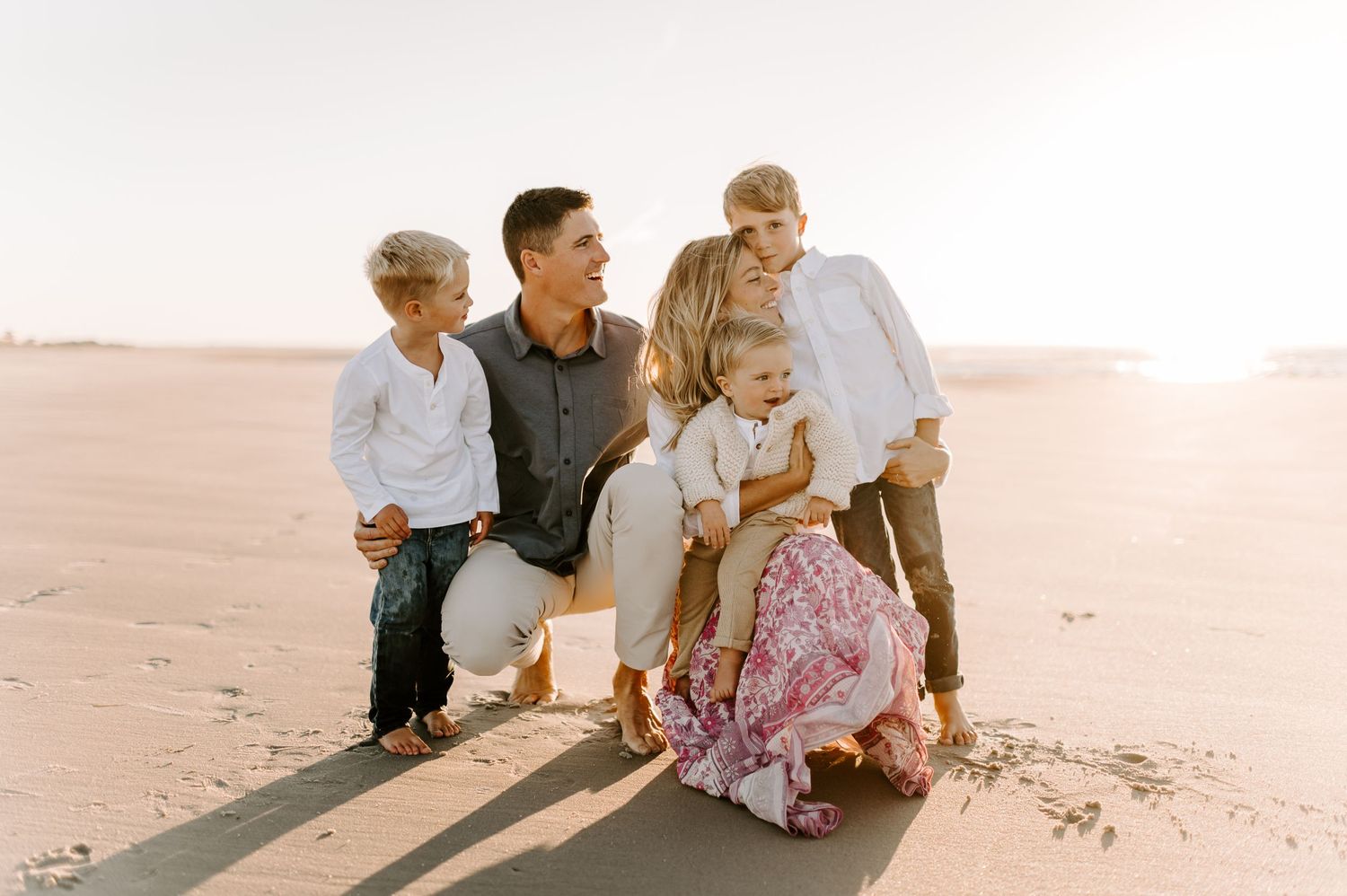 Family sitting together on beach during golden hour.