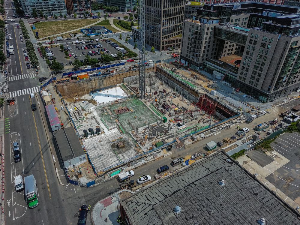 Aerial view of urban construction site with surrounding high-rise buildings and streets.