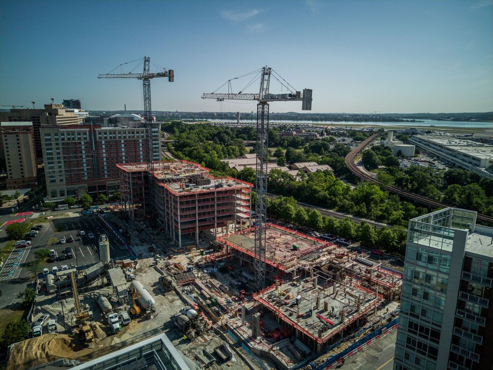 Construction cranes tower over a waterfront development project with partially completed buildings.