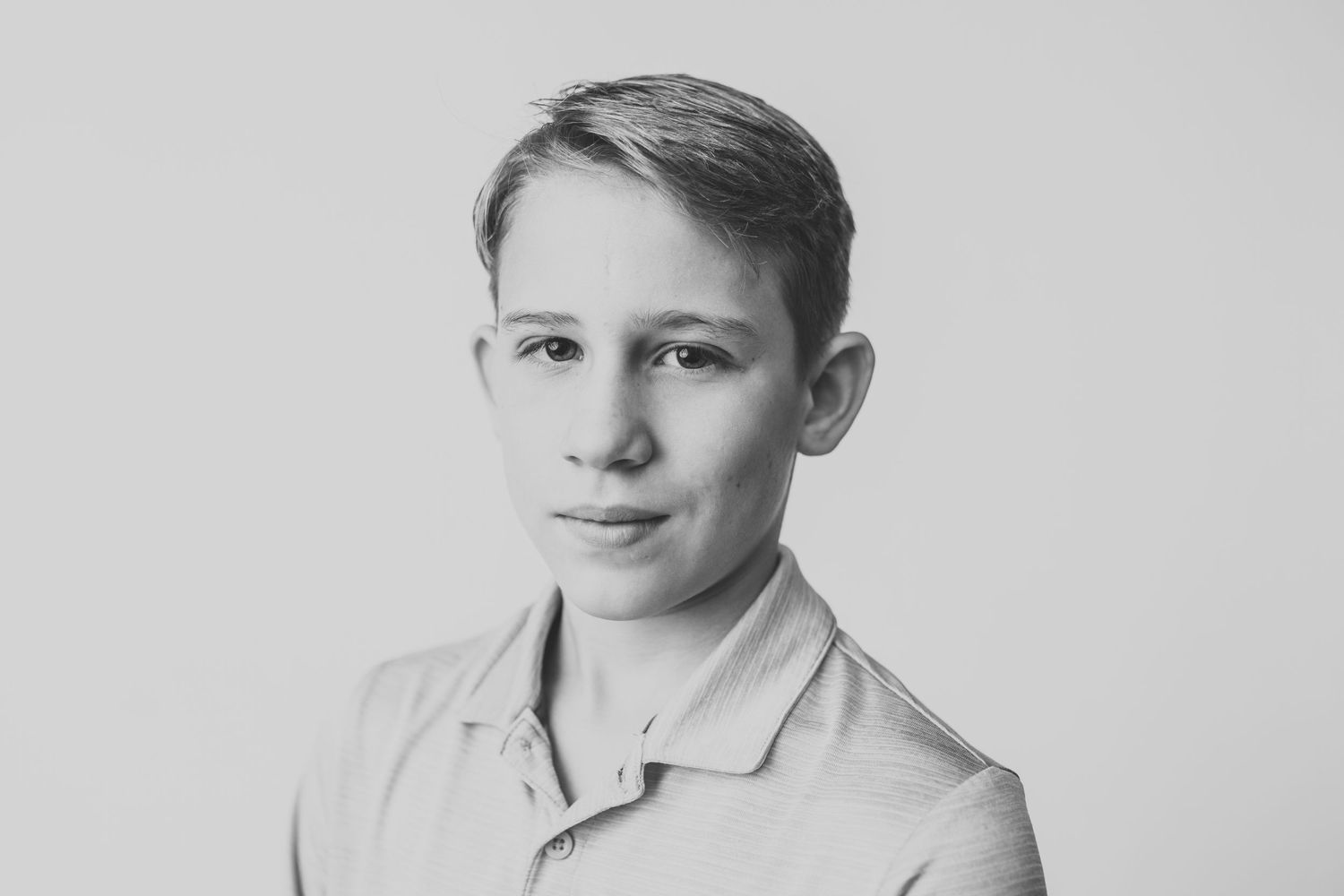 Black and white studio portrait in collared shirt with gentle smile.