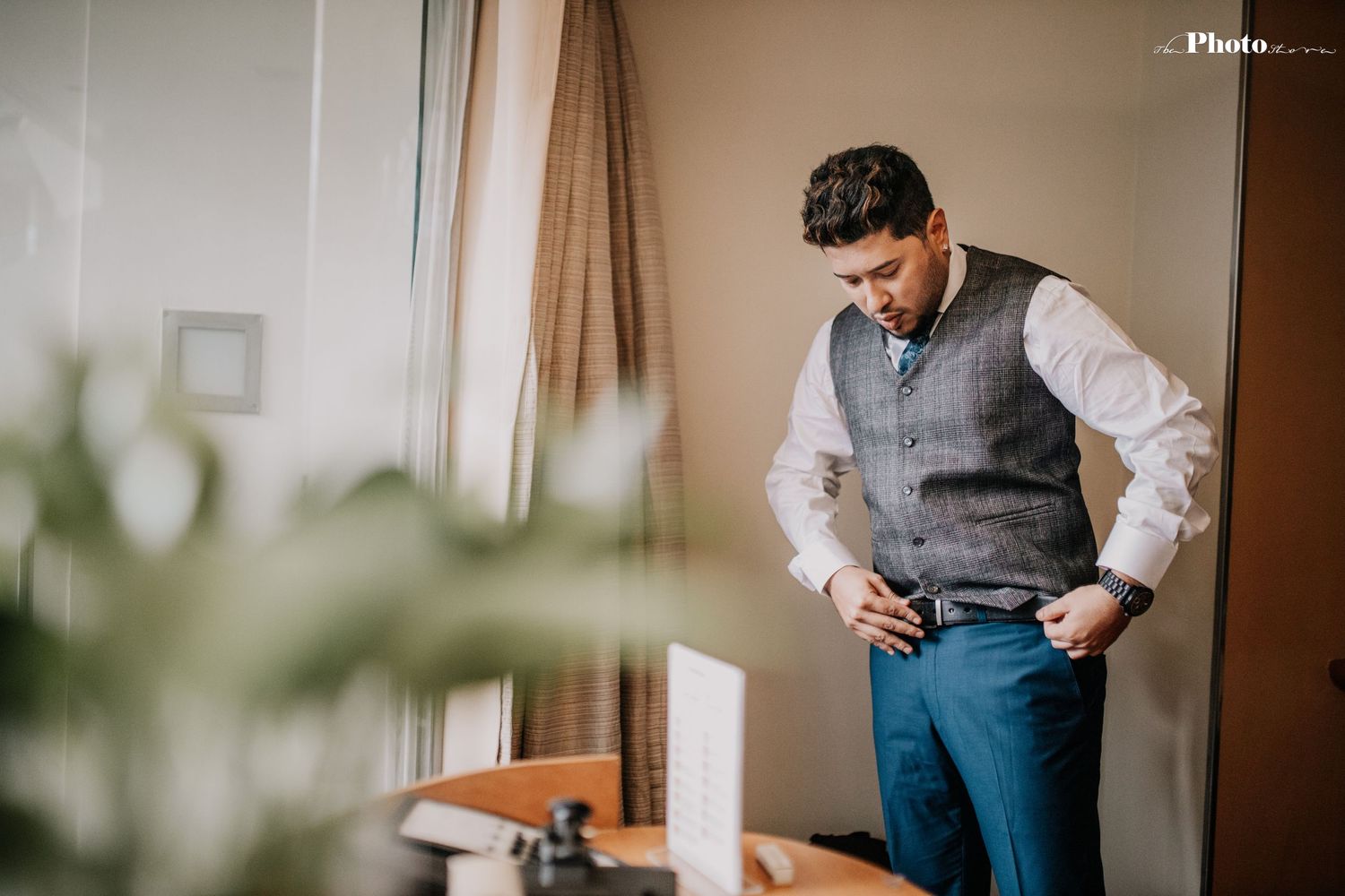 Formal attire preparation scene in a warmly lit hotel room.