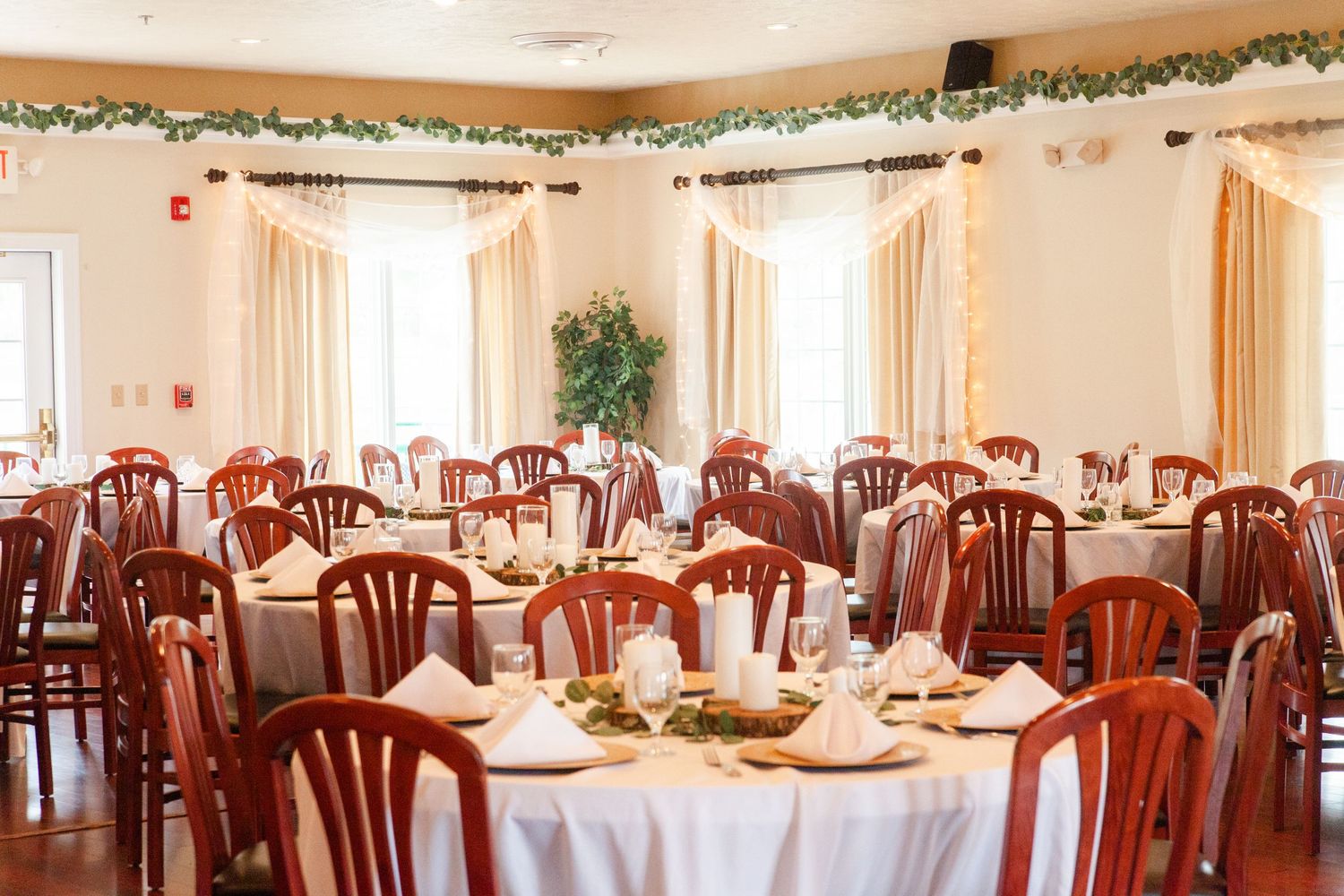 Elegant wedding reception venue with traditional wooden chairs and white tablecloths set for dining.