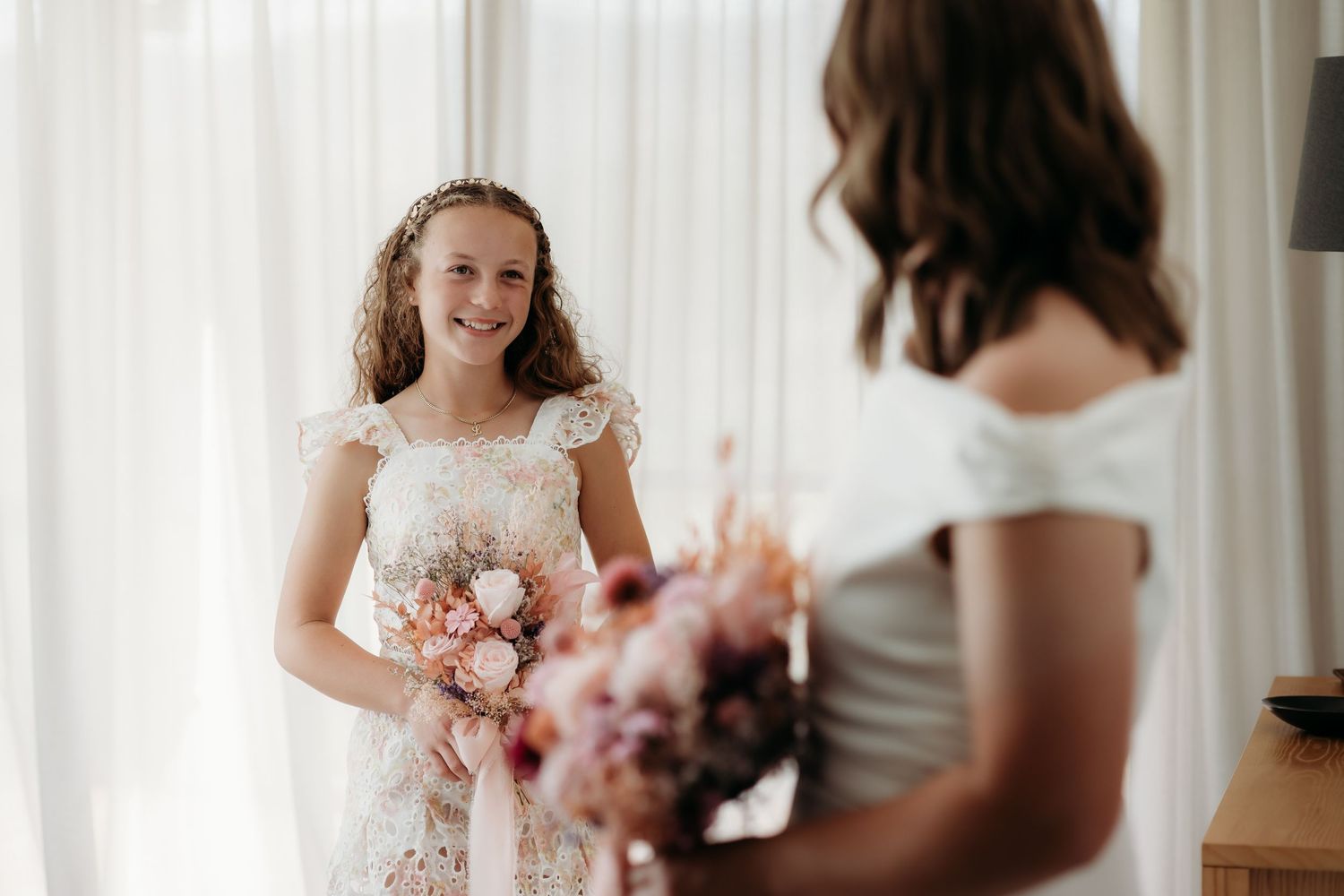 Elegant wedding scene with soft white curtains and pink floral bouquets.