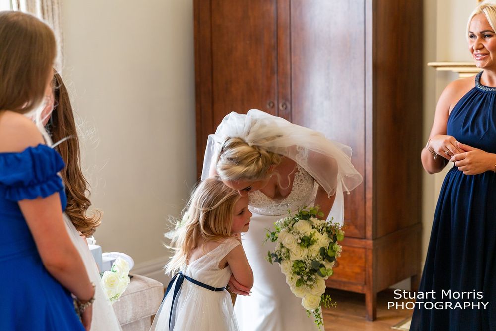 Young flower girl gets a kiss of her mum the bride on the wedding morning. Lancashire wedding photographer.