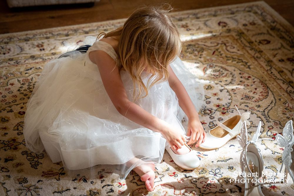 Young flowergirl puts on her shoes during bridal prep. West tower wedding photographer. Lancashire wedding photography.