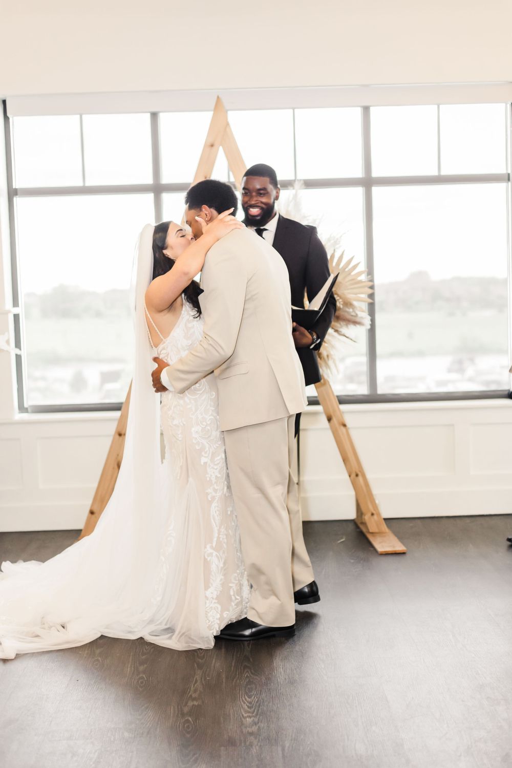Wedding ceremony moment captured in front of triangular wooden arch backdrop.