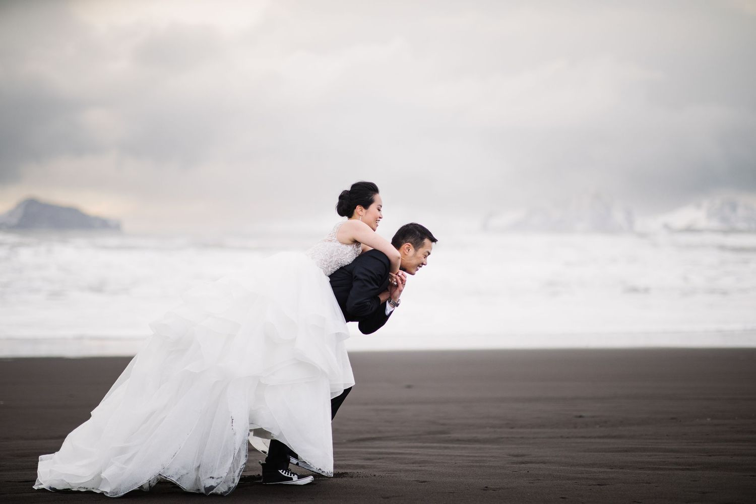 A couple in formal attire dancing on a misty beach.