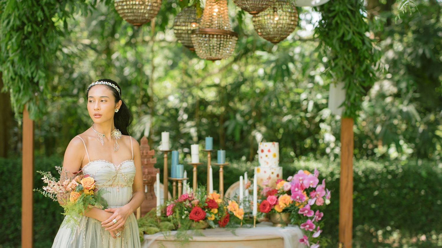 Garden wedding dessert table with chandeliers and floral decorations.
