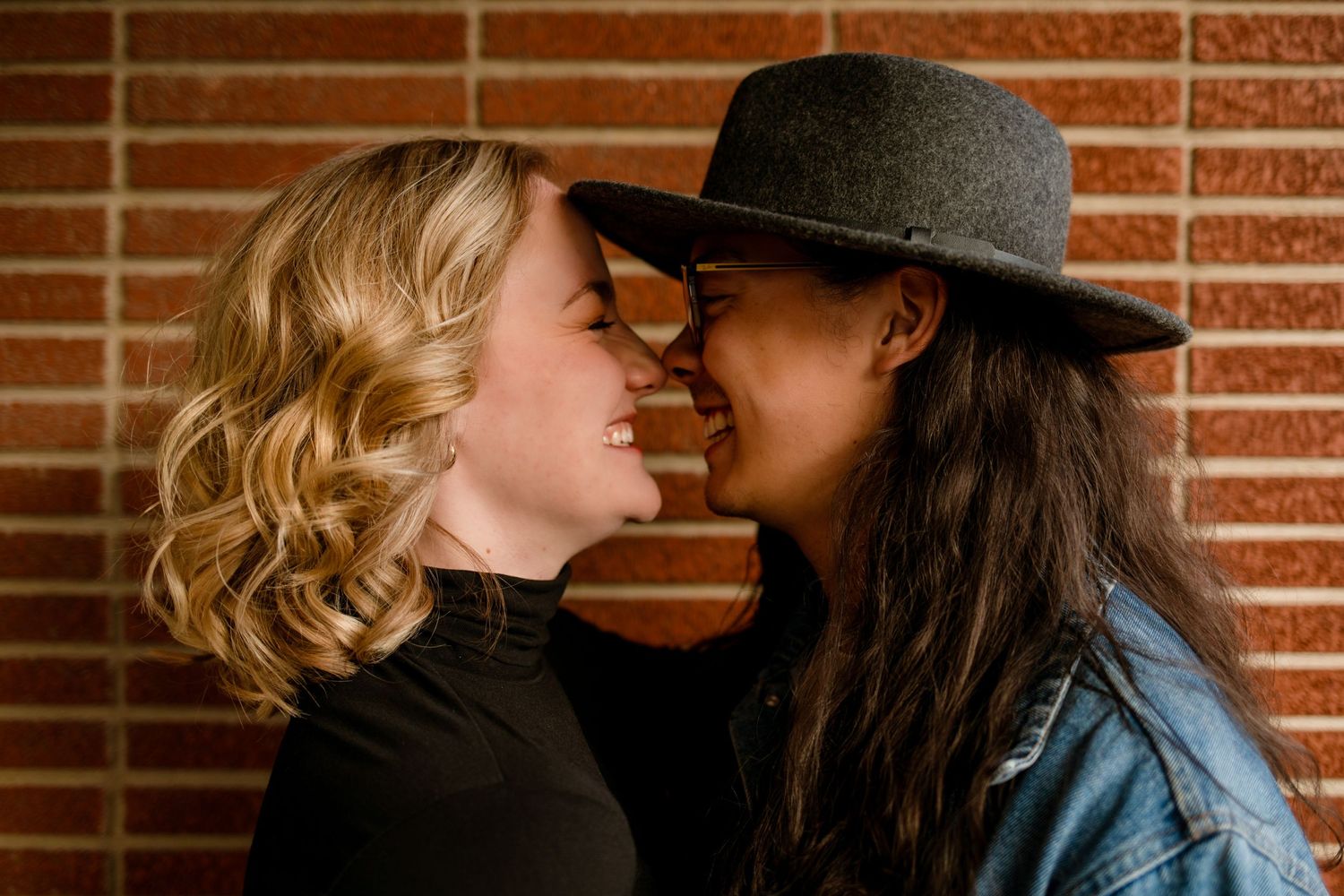 An intimate moment shared between two people against a brick wall background.