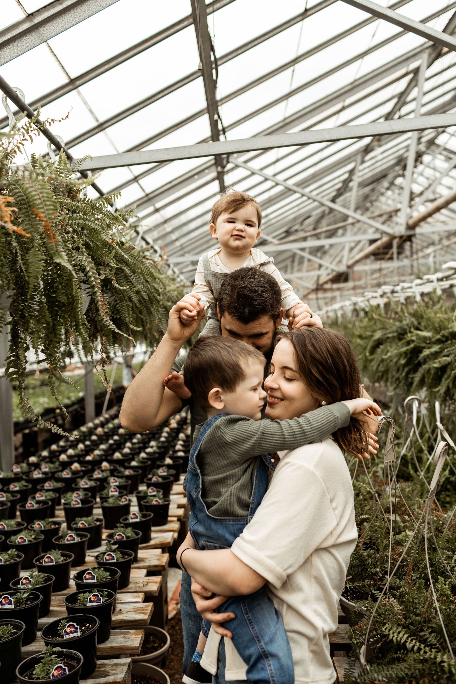 Family sharing joyful moment together in greenhouse filled with plants.