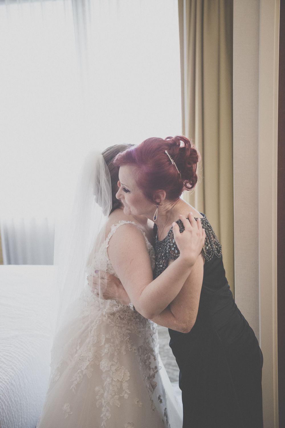 Wedding dress being fastened in a sunlit room with elegant details.